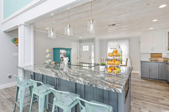 kitchen with white cabinetry, stone counters, pendant lighting, decorative backsplash, and light wood-type flooring