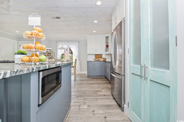 kitchen with wooden ceiling, backsplash, white cabinets, hanging light fixtures, and appliances with stainless steel finishes