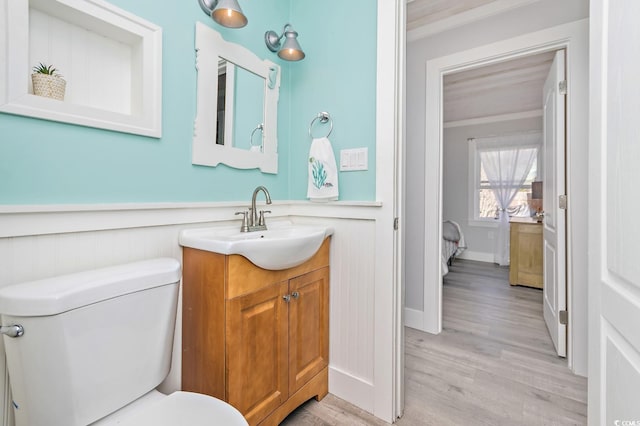 bathroom featuring hardwood / wood-style flooring, crown molding, vanity, and toilet