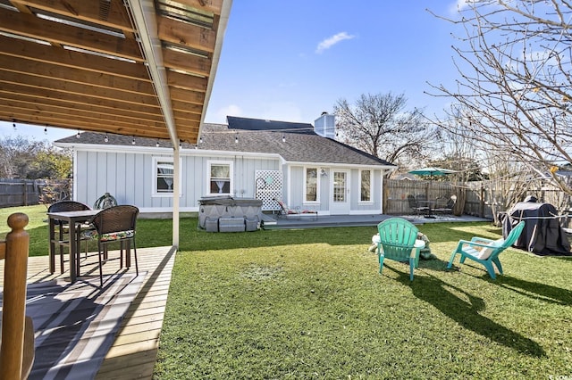 rear view of property with a yard, a hot tub, and a patio area