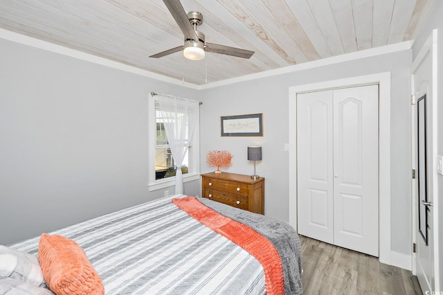 bedroom with light wood-type flooring, wood ceiling, ceiling fan, crown molding, and a closet