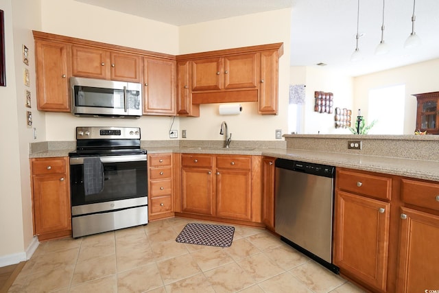 kitchen with appliances with stainless steel finishes, sink, light tile patterned floors, and light stone countertops