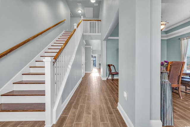 stairway featuring crown molding, a healthy amount of sunlight, and hardwood / wood-style flooring