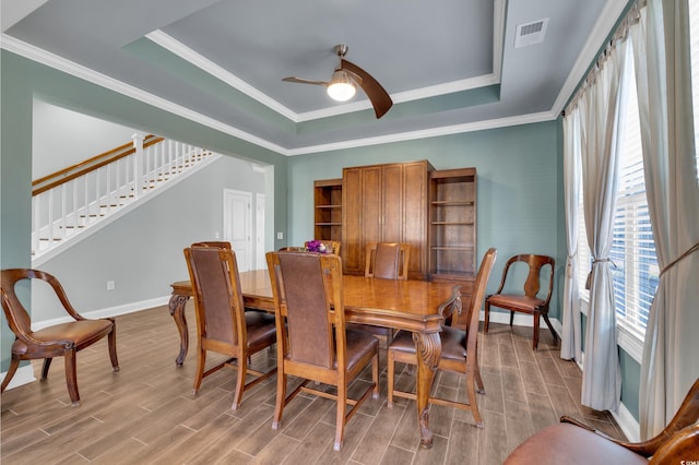 dining room with a raised ceiling, ceiling fan, and ornamental molding