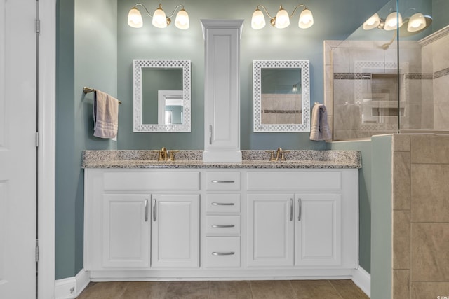 bathroom with tile patterned flooring, vanity, and a tile shower