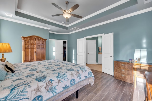 bedroom featuring ceiling fan, a spacious closet, ornamental molding, and a tray ceiling