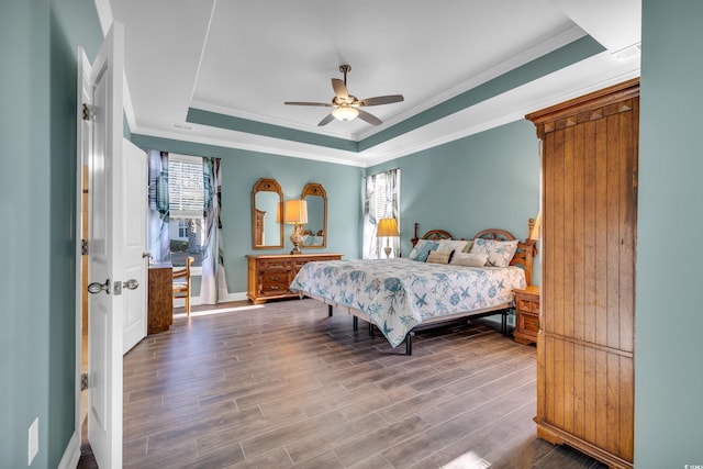 bedroom featuring multiple windows, wood-type flooring, a raised ceiling, and ceiling fan