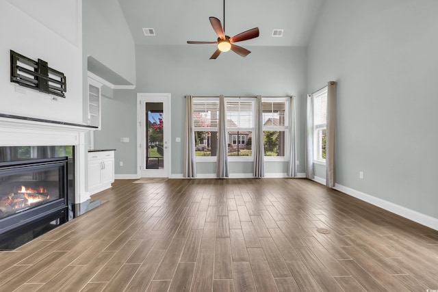 1405 Osprey Pointe Ln, North Myrtle Beach, SC 29582 - unfurnished living room with high vaulted ceiling, a glass covered fireplace, ceiling fan, and wood finished floors