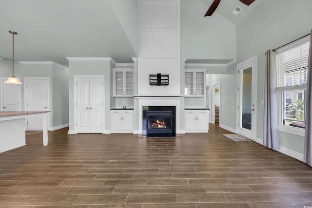 1405 Osprey Pointe Ln, North Myrtle Beach, SC 29582 - unfurnished living room featuring a ceiling fan, high vaulted ceiling, a fireplace with flush hearth, dark wood-style flooring, and crown molding