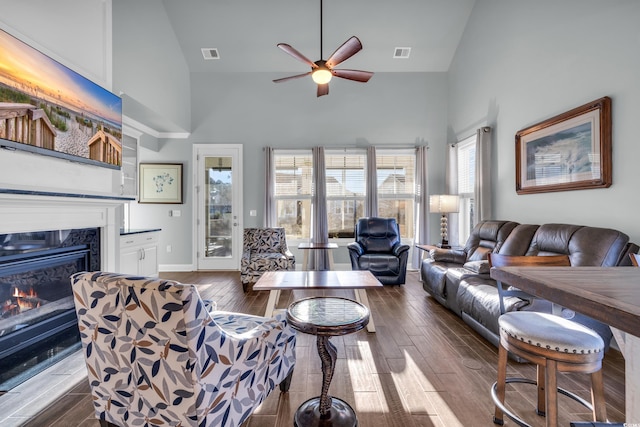 living room featuring ceiling fan, a fireplace, high vaulted ceiling, and dark wood-type flooring