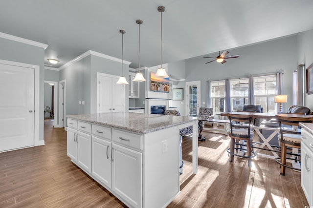 1405 Osprey Pointe Ln, North Myrtle Beach, SC 29582 - kitchen with a glass covered fireplace, light wood finished floors, ceiling fan, white cabinets, and a center island