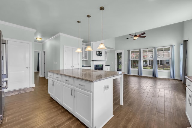 1405 Osprey Pointe Ln, North Myrtle Beach, SC 29582 - kitchen with a fireplace, a ceiling fan, dark wood-style flooring, white cabinetry, and ornamental molding