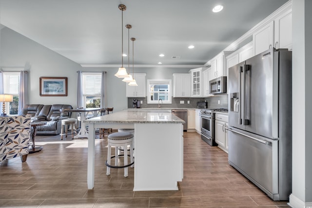 kitchen featuring a center island, pendant lighting, high quality appliances, a breakfast bar, and white cabinets