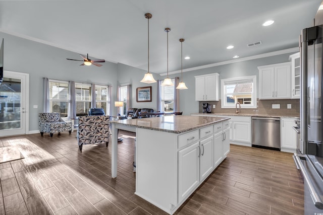 kitchen featuring white cabinetry, a center island, stainless steel appliances, and light stone counters