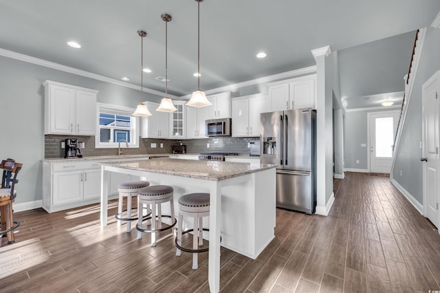 kitchen with white cabinetry, a breakfast bar, a kitchen island, and stainless steel appliances