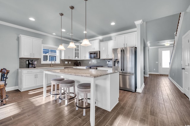1405 Osprey Pointe Ln, North Myrtle Beach, SC 29582 - kitchen with stainless steel appliances, a kitchen island, white cabinets, glass insert cabinets, and backsplash