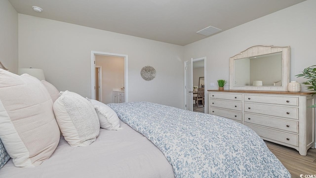 bedroom featuring connected bathroom and light wood-type flooring