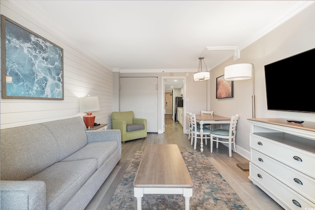 living room featuring wooden walls, light wood-type flooring, and ornamental molding