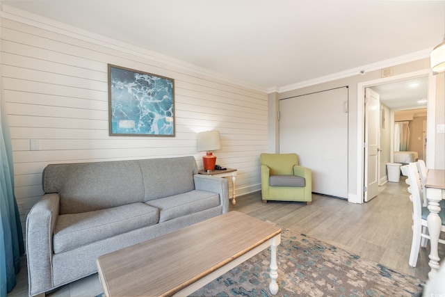 living room with wood walls, wood-type flooring, and ornamental molding