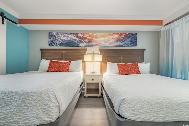 bedroom with crown molding, a barn door, and wood finished floors