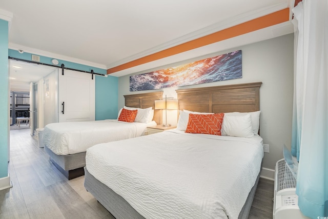 bedroom featuring hardwood / wood-style floors, a barn door, and crown molding