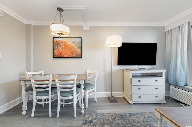 dining room featuring a wall mounted AC, wood finished floors, baseboards, and ornamental molding