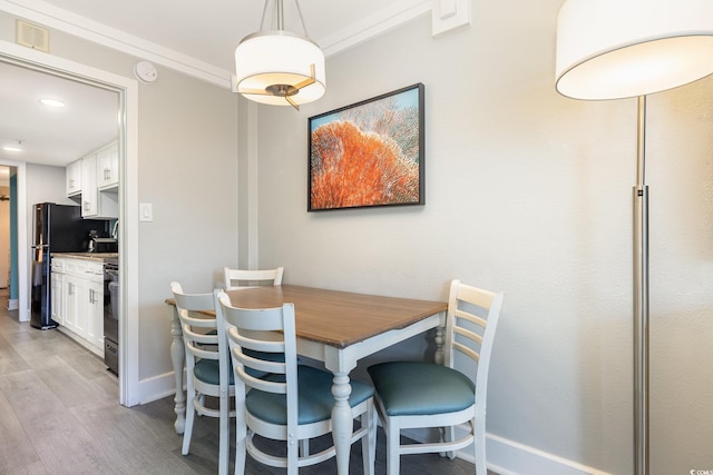 dining area with light hardwood / wood-style floors and ornamental molding