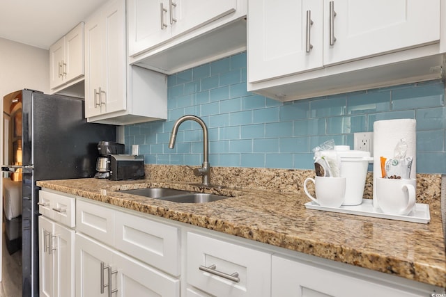 kitchen featuring white cabinetry, light stone countertops, backsplash, and a sink