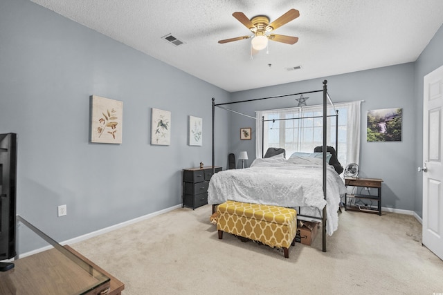 carpeted bedroom with ceiling fan and a textured ceiling