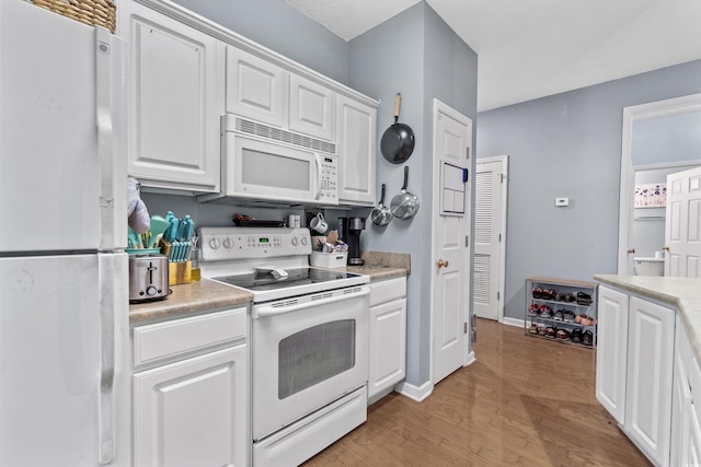 kitchen featuring white cabinets, light hardwood / wood-style floors, and white appliances