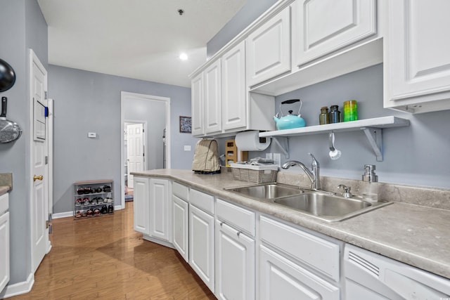 kitchen with light hardwood / wood-style flooring, white cabinetry, and sink