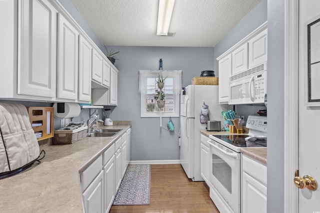 kitchen featuring white cabinetry, sink, light hardwood / wood-style flooring, a textured ceiling, and white appliances