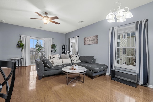 living room featuring wood-type flooring and ceiling fan with notable chandelier