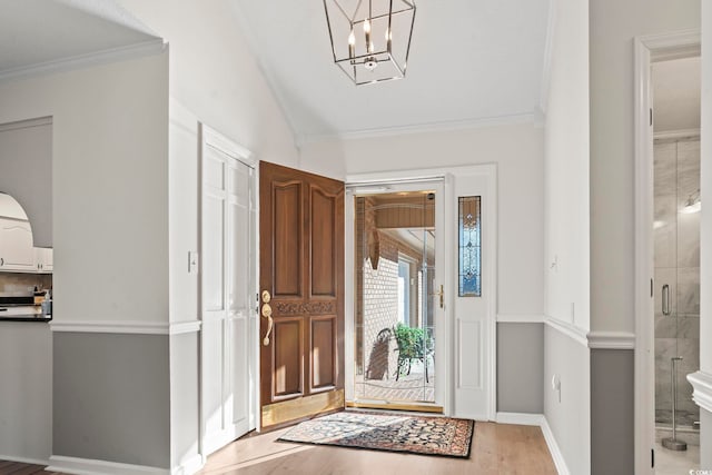 entryway featuring wood-type flooring, an inviting chandelier, and ornamental molding