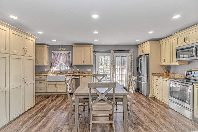 kitchen featuring appliances with stainless steel finishes, sink, hardwood / wood-style flooring, and cream cabinets