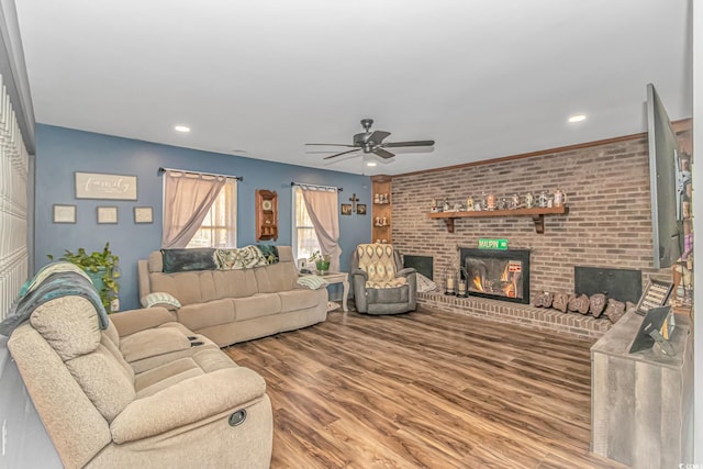 living room featuring hardwood / wood-style flooring, a brick fireplace, ceiling fan, and brick wall