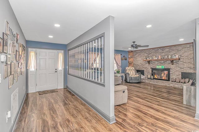 entrance foyer featuring hardwood / wood-style floors, ceiling fan, and a fireplace