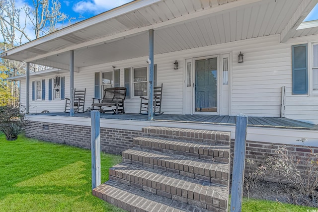 entrance to property featuring a porch and a yard