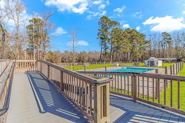 wooden deck featuring a covered pool, a storage unit, and a lawn