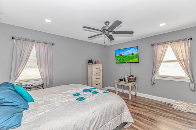 bedroom with hardwood / wood-style flooring, ceiling fan, and multiple windows