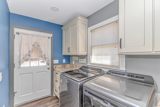 laundry area with washer and clothes dryer, cabinets, plenty of natural light, and light hardwood / wood-style floors