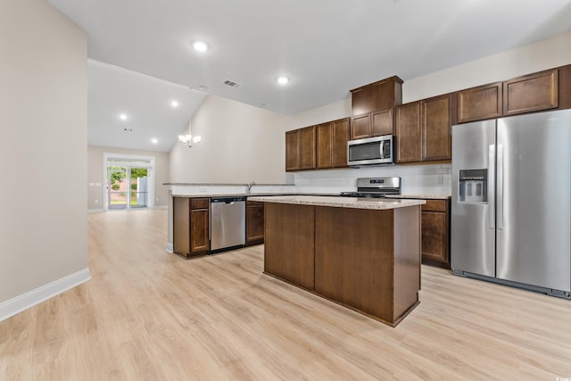 kitchen with a kitchen island, dark brown cabinets, stainless steel appliances, and light wood-type flooring