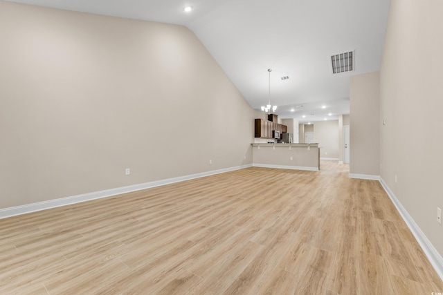 unfurnished living room with a chandelier, vaulted ceiling, and light wood-type flooring