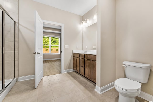 bathroom featuring a shower with door, vanity, tile patterned flooring, and toilet