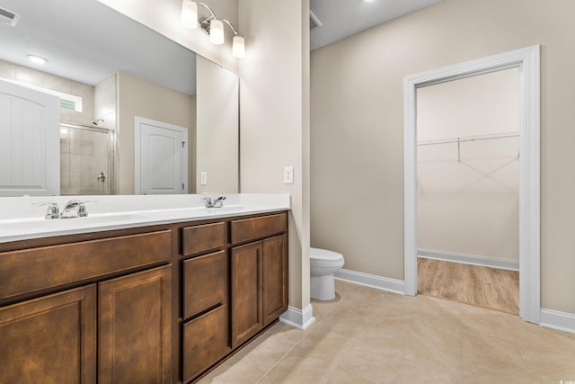 bathroom featuring tile patterned floors, toilet, a shower with door, and vanity