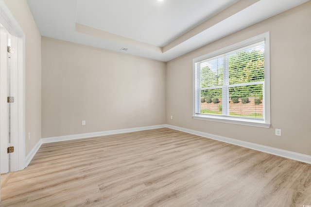 unfurnished room with a tray ceiling and light hardwood / wood-style flooring