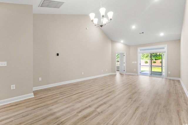 empty room with a notable chandelier, high vaulted ceiling, and light hardwood / wood-style flooring