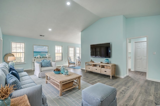 living room with a wealth of natural light, hardwood / wood-style floors, and vaulted ceiling