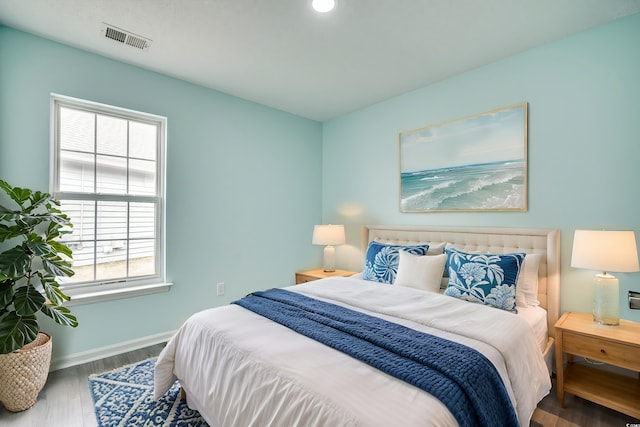 bedroom with hardwood / wood-style flooring and multiple windows