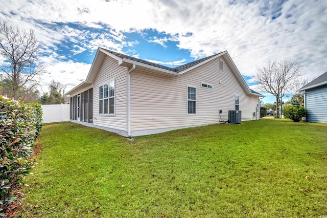 view of side of property featuring a lawn, a sunroom, and central air condition unit